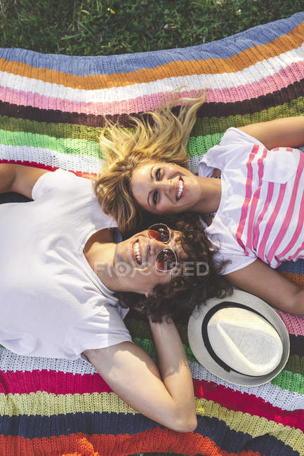 Happy young couple lying on blanket in park — Stock Photo