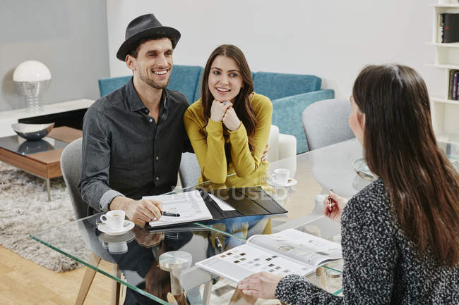 Portrait of couple consulting with shop assistant — Stock Photo
