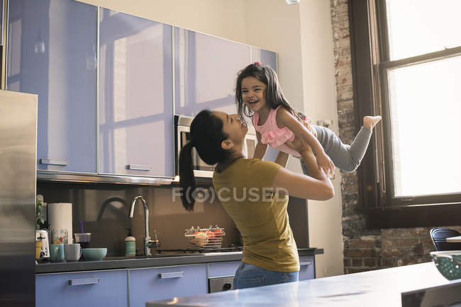 Mother Holding Aloft Her Toddler Daughter Standing By Kitchen Table Playing Child Stock Photo 173602548