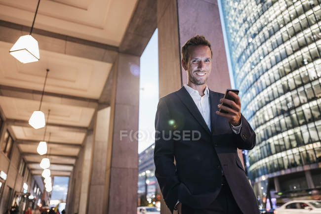 Alemanha, Berlim, retrato de um empresário sorridente caminhando em Potsdamer Platz à noite — Fotografia de Stock