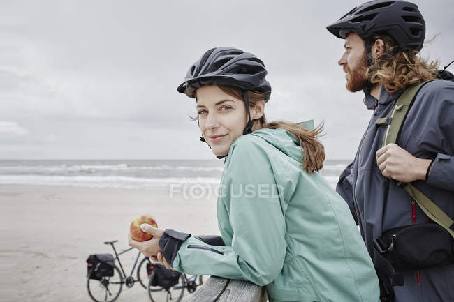 Casal em uma viagem de bicicleta ter uma pausa no molhe na praia — Fotografia de Stock