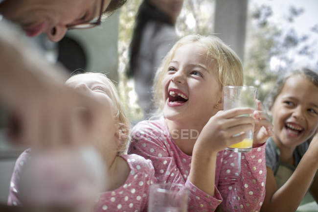 Caucásico lindo niñas beber jugo en cocina - foto de stock