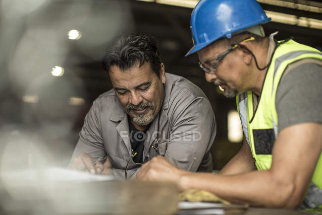 Ingenieros discutiendo planes de construcción en taller - foto de stock