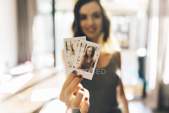 Young woman holding polaroids of herself, showing at camera — Stock Photo