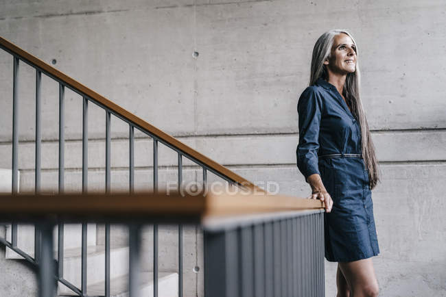 Lächelnde Frau mit langen grauen Haaren im Treppenhaus — Stockfoto