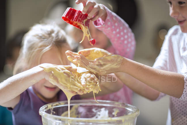 Smiling girls  messing with dough in kitchen — Stock Photo