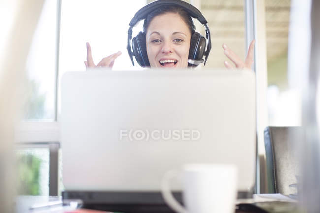 Donna felice alla scrivania con laptop e auricolare — Foto stock