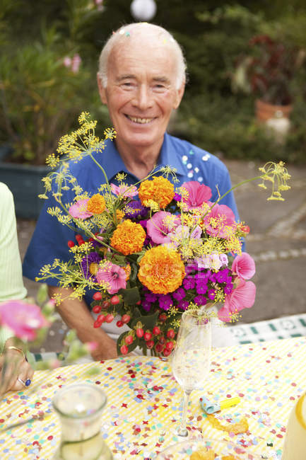 Uomo anziano seduto a tavola con mazzo di fiori — adulti anziani, Vecchio -  Stock Photo