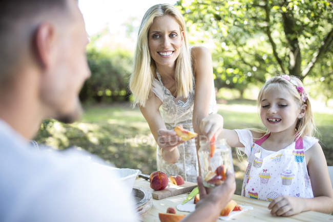 Glückliche Familie bewahrt Pfirsiche im Garten — Stockfoto