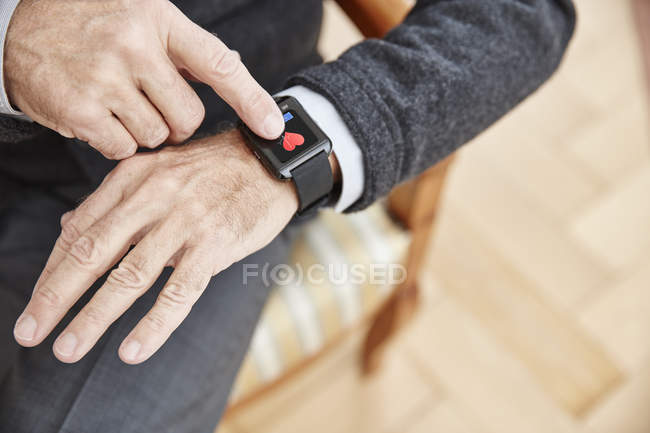 Hombre mayor revisando datos médicos en smartwatch - foto de stock