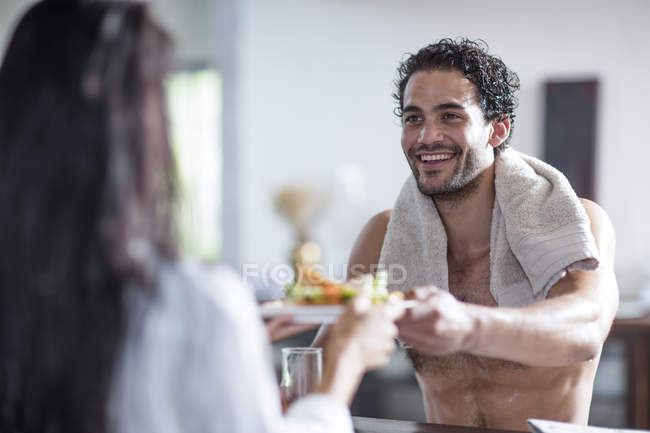 Smiling young couple at home eating sandwiches — Stock Photo