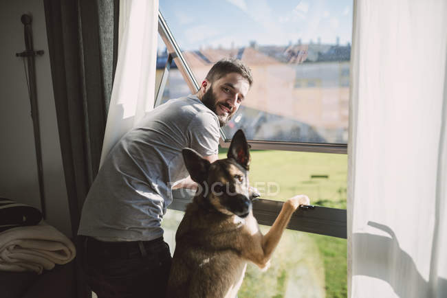 Young man and his dog in the window at home, Spain — Stock Photo