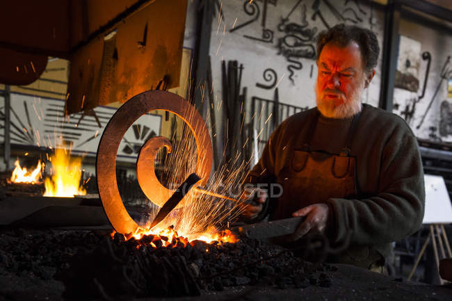 Коваль на роботі в свою майстерню, робота з металевих деталей на вогні — стокове фото