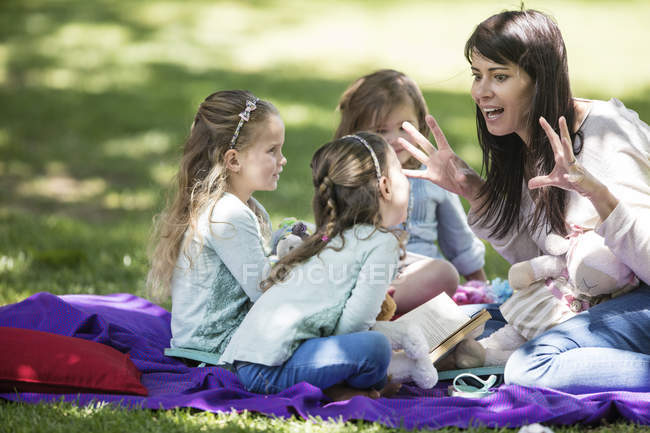 Family picnic story telling outside garden — Stock Photo