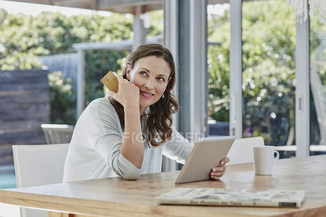 Портрет улыбающейся женщины, держащей планшет и кредитку — стоковое фото