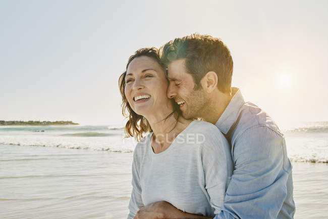 Ritratto di coppia sorridente che abbraccia sulla spiaggia — Foto stock