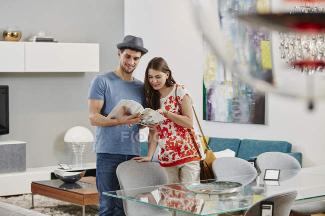 Portrait of couple looking at catalog in furniture store — Stock Photo