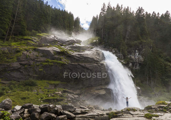 Femme avec les bras levés debout près des chutes d'eau Krimml à Salzbourg, Autriche — Photo de stock