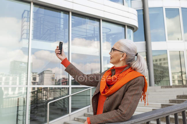 Fashionable mature woman taking selfie with cell phone — Stock Photo