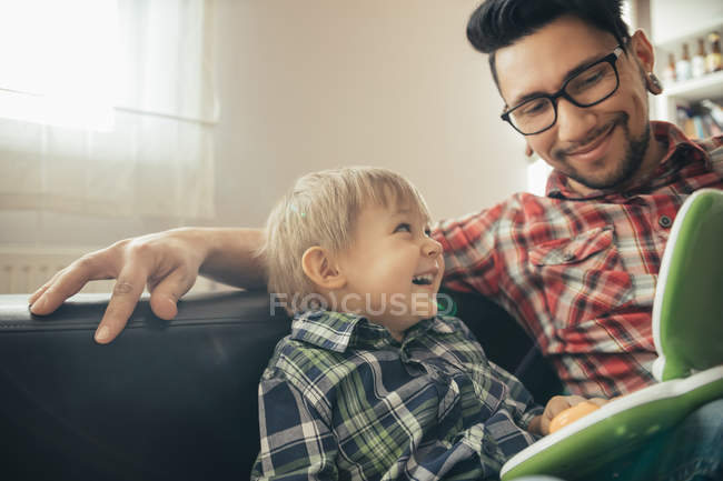 Feliz padre e hijo con computadora portátil de juguete - foto de stock
