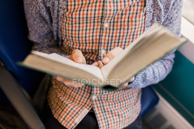 Молодой человек читает книгу, частичный взгляд — стоковое фото