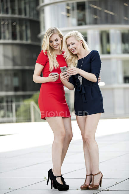 Deux femmes à la mode regardant leurs smartphones — Photo de stock