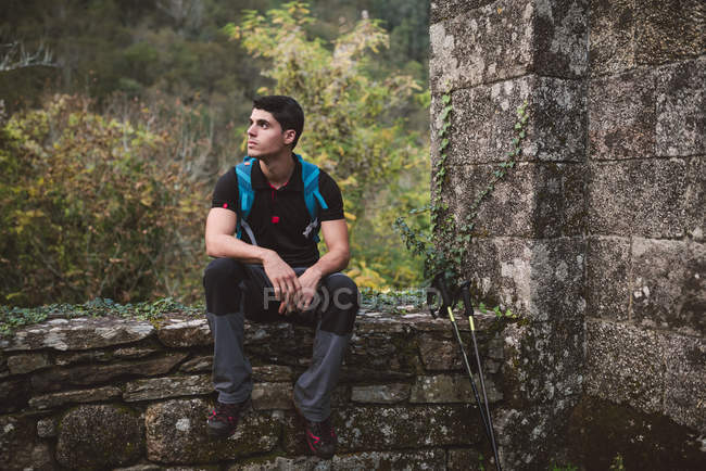 Hiker man resting on stone wall in nature — Stock Photo