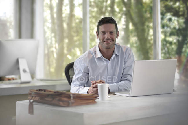 Man Sitting At Desk In Modern Office Bag Technology Stock