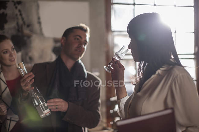 Woman tasting wine in restaurant and man holding bottle — Stock Photo