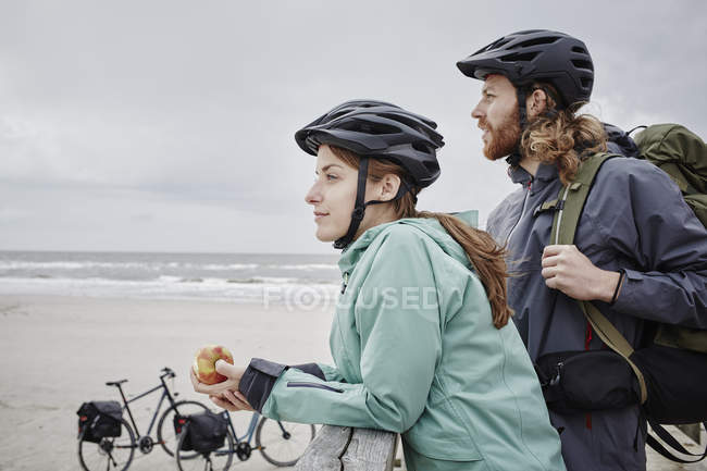Coppia in gita in bicicletta con una pausa sul molo in spiaggia — Foto stock