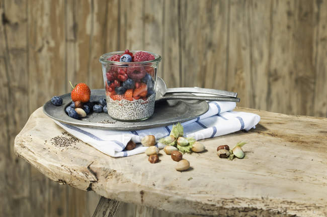 Glasses of chia pudding with different berries, pomegranate seeds and hazelnuts — Stock Photo