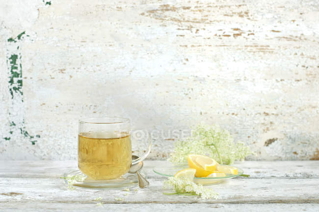Verre de thé aux fleurs de sureau, de fleurs de sureau et de tranches de citron — Photo de stock