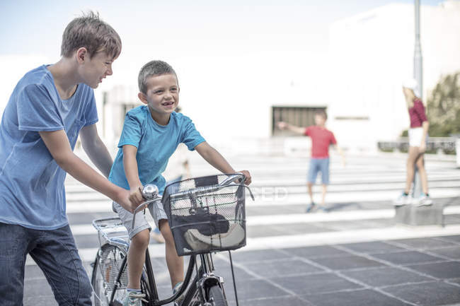 Niño enseñando a su hermano pequeño a montar en bicicleta - foto de stock