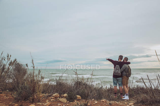 Jovem gay casal de pé no mar costa e olhando para vista — Fotografia de Stock