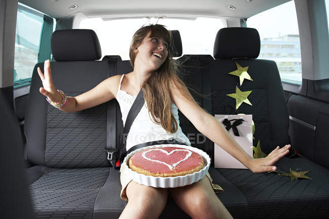 Menina feliz n carro com bolo em forma de coração — Fotografia de Stock