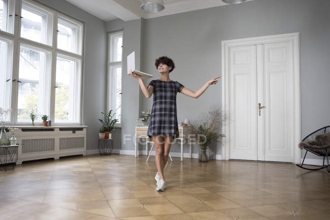 Giovane donna in piedi con computer portatile a casa — Foto stock