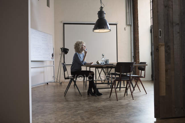 Frau sitzt im Sitzungssaal am Tisch und denkt nach — Stockfoto