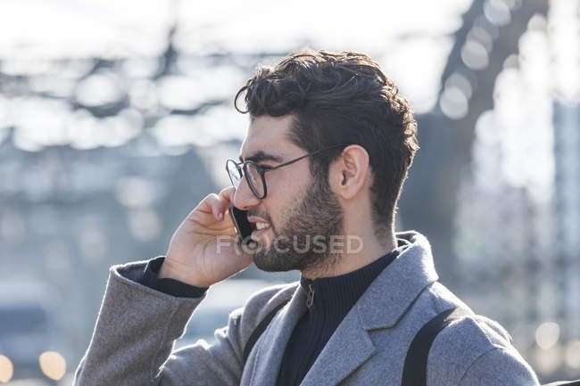 Portrait de jeune homme d'affaires avec sac à dos au téléphone — Photo de stock