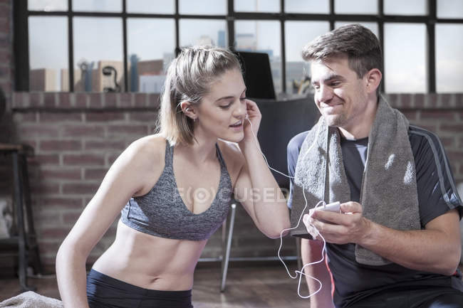 Junge Männer und Frauen mit Kopfhörern sitzen im Fitnessraum — Stockfoto