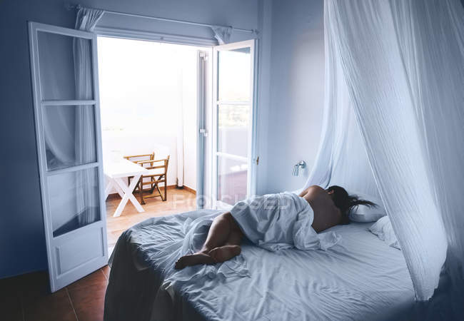 Woman sleeping in white sheets with open balcony door — Stock Photo