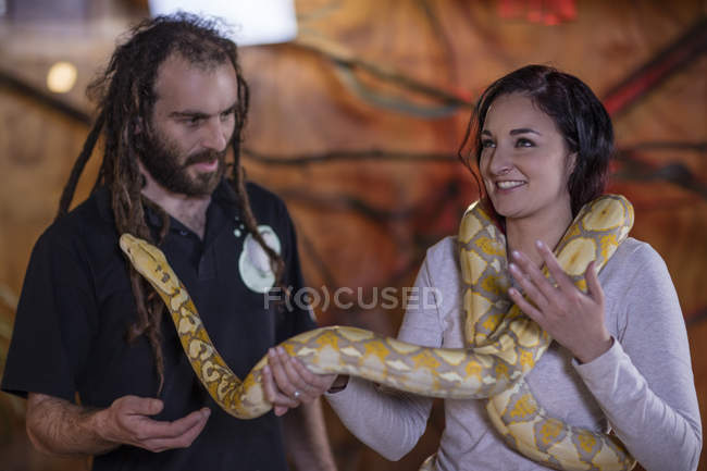 Asistente de animales entregando serpiente de pitón albina a la mujer - foto de stock