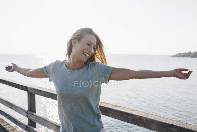 Счастливая молодая женщина на пристани при подсветке — стоковое фото