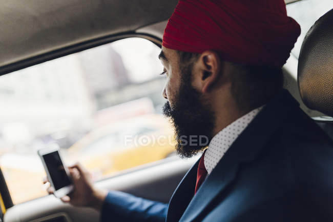 Indischer Geschäftsmann sitzt im Taxi und nutzt Smartphone — Stockfoto