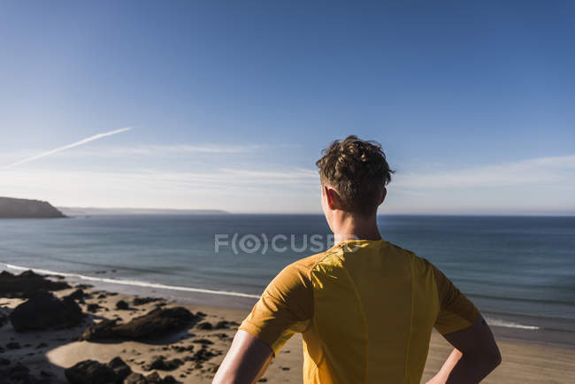 Jovem esportivo na costa olhando para a vista, frança, península de crozon — Fotografia de Stock