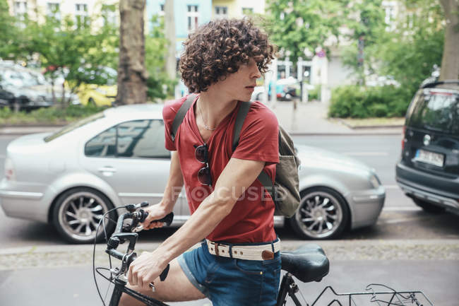 Jeune homme faisant du vélo sur la chaussée et se retournant — Photo de stock