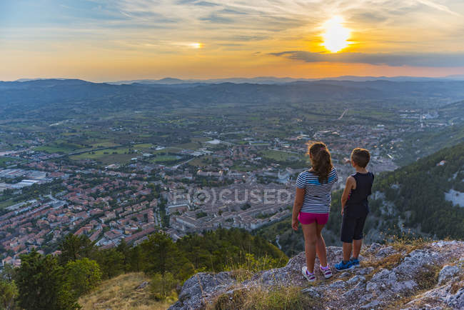 Італія, Gubbio, спині перегляд двох дітей, дивлячись на місто зверху — стокове фото
