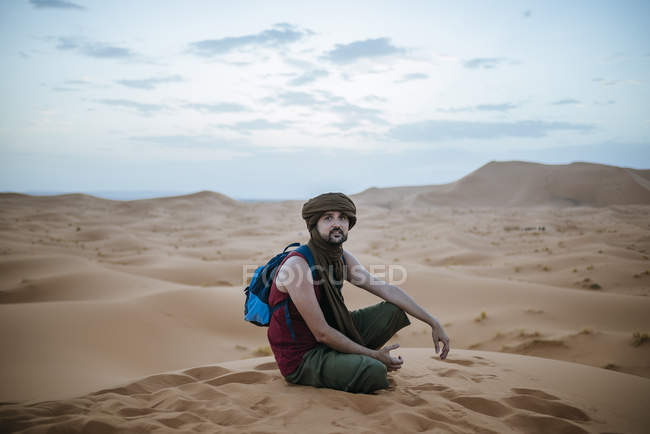 Turista con turbante seduto nel deserto — Foto stock