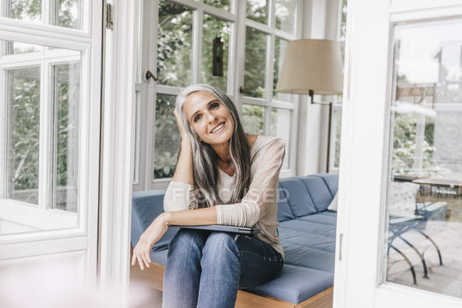 Donna sorridente seduta sul salotto — Foto stock