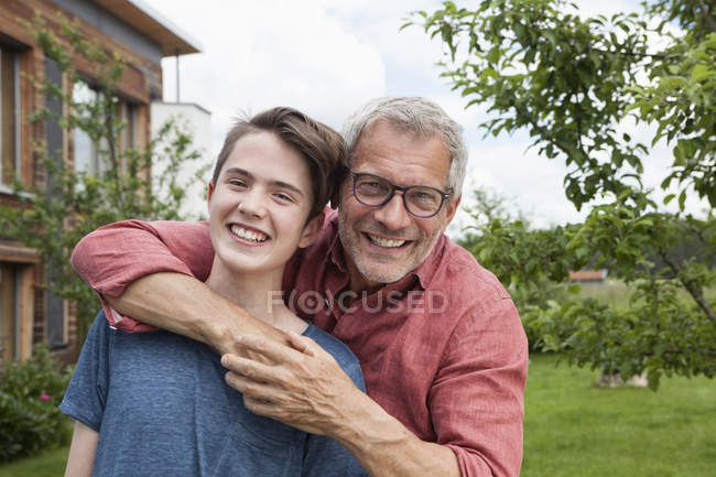 Portrait of happy father and son standing in garden — Stock Photo