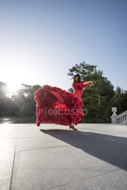 Femme vêtue de flamenco dansant en rouge sur la terrasse au contre-jour — Photo de stock